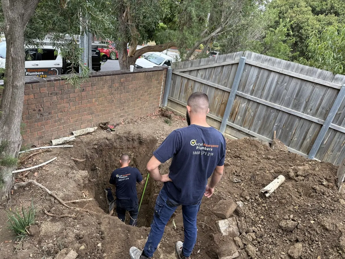 Plumber working on an excavated drain, Braeside