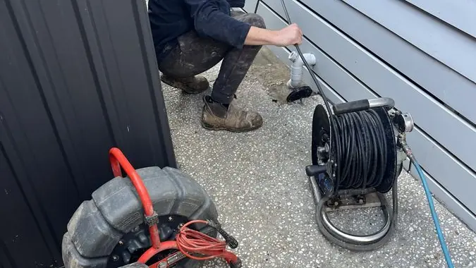 Drain inspection equipment beside a plumber, Braeside